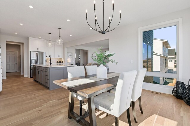 dining room featuring light wood-type flooring, a notable chandelier, and recessed lighting