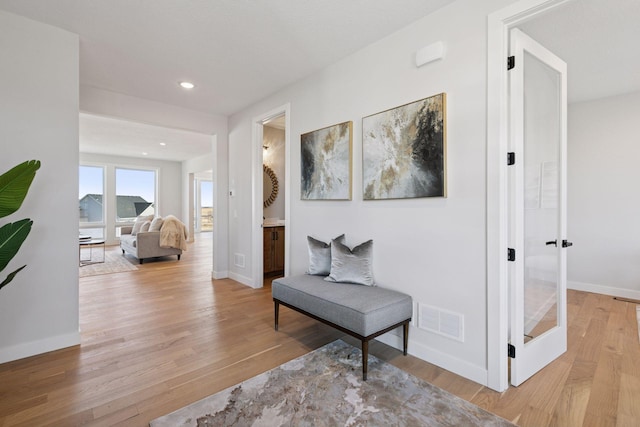 hallway with light wood-type flooring, visible vents, and baseboards