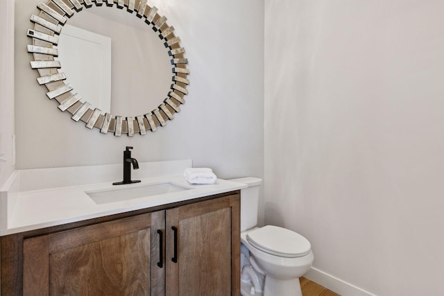 bathroom featuring toilet, baseboards, and vanity