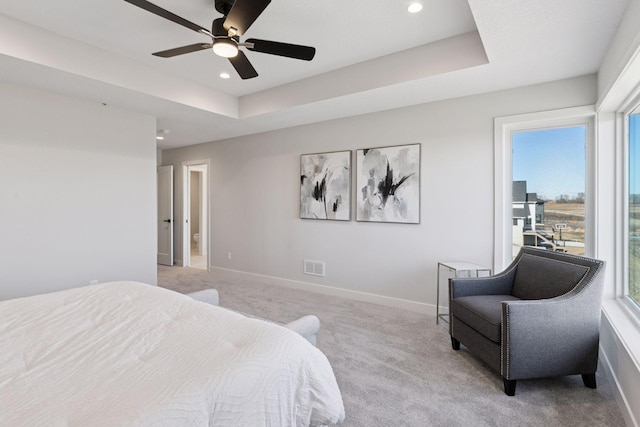 bedroom with a tray ceiling, recessed lighting, light colored carpet, and baseboards