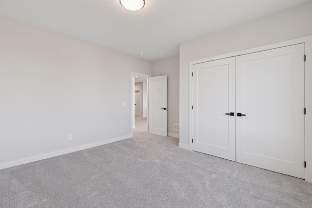 unfurnished bedroom with carpet, a closet, and baseboards