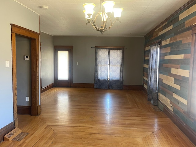 unfurnished room featuring baseboards, visible vents, a notable chandelier, and ornamental molding