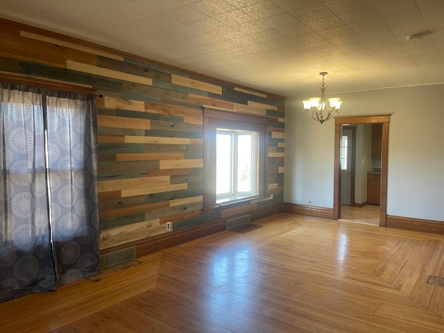 interior space with visible vents, a notable chandelier, baseboards, and wood finished floors