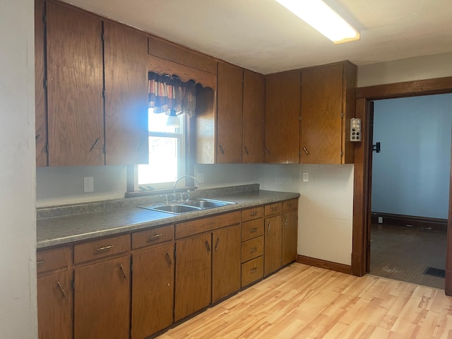 kitchen with dark countertops, visible vents, a sink, and light wood-style flooring