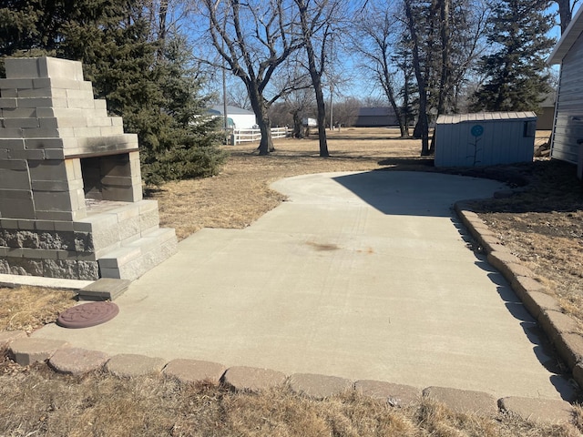 view of yard with a patio area, a shed, an outdoor fireplace, and an outbuilding