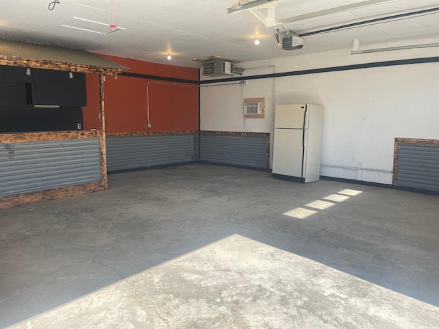 garage with a garage door opener, freestanding refrigerator, and a wall mounted air conditioner