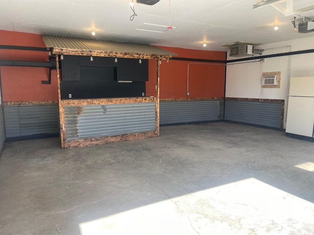 garage with a wall mounted AC, freestanding refrigerator, and a garage door opener