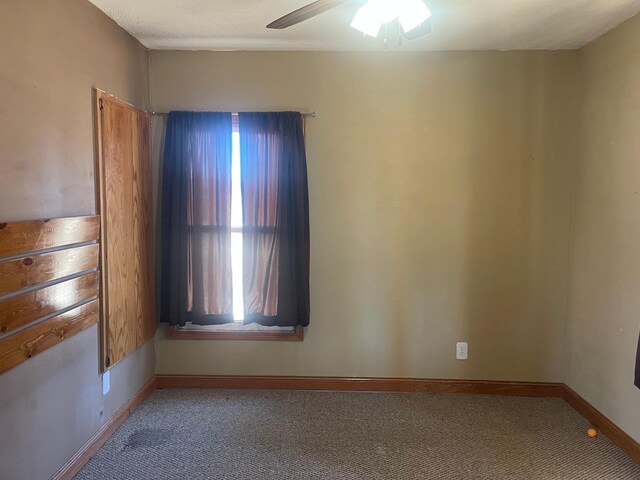 empty room featuring carpet floors, ceiling fan, and baseboards