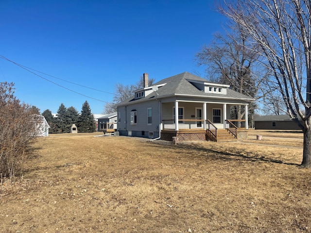 view of front facade featuring covered porch, a chimney, and a front yard