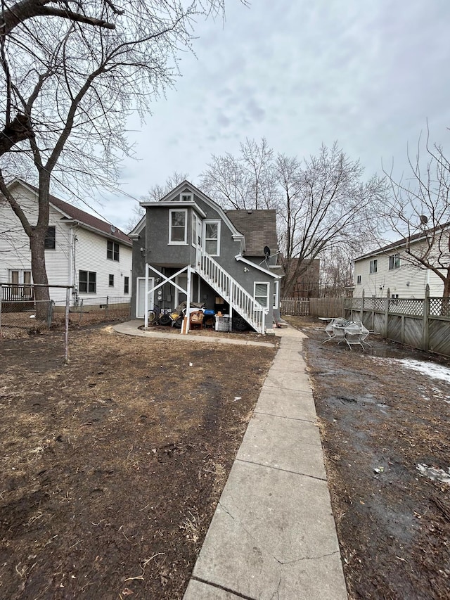 back of property featuring stairway and fence