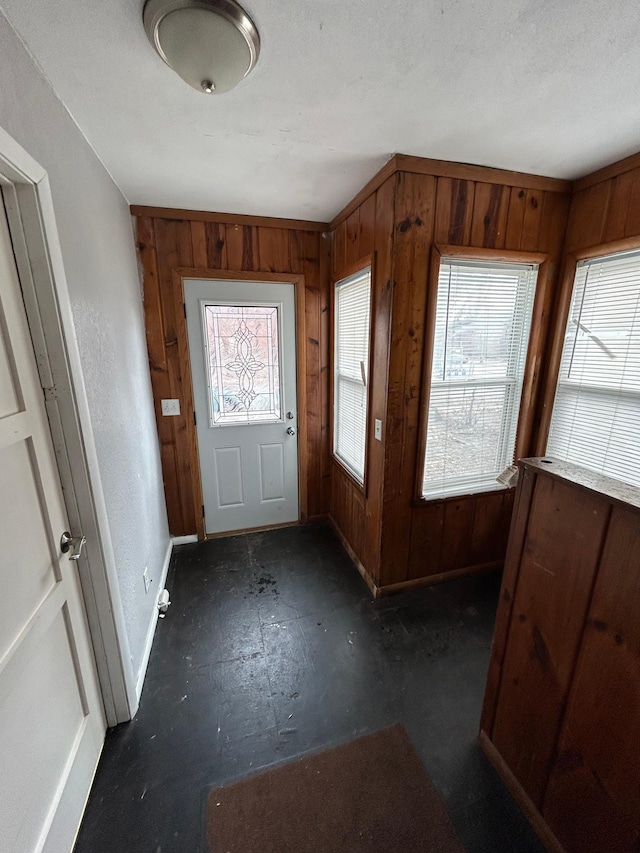 foyer entrance featuring wood walls and baseboards