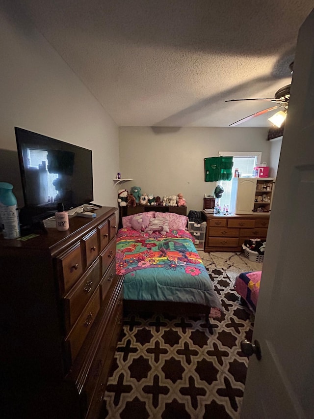 bedroom with carpet floors, a ceiling fan, and a textured ceiling