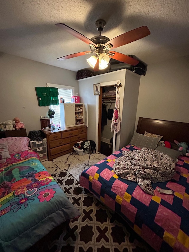 bedroom with carpet floors, a closet, a spacious closet, ceiling fan, and a textured ceiling