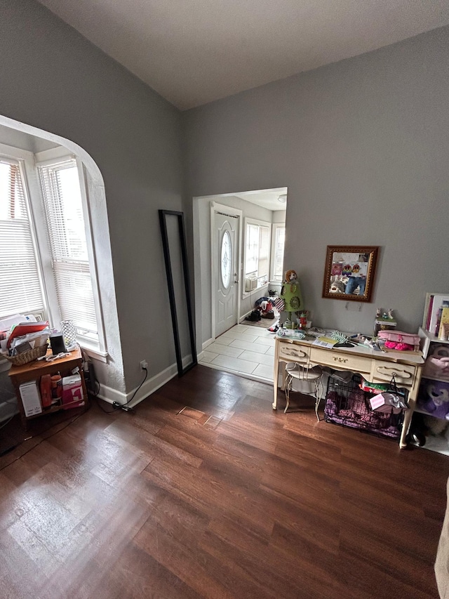 foyer entrance featuring arched walkways, baseboards, and wood finished floors