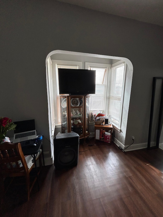 living room with arched walkways, wood finished floors, and baseboards