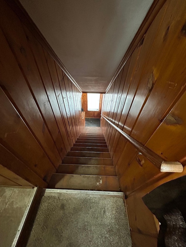 stairway featuring wooden walls