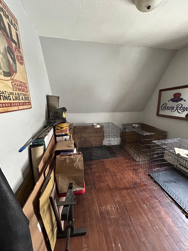 interior space with lofted ceiling, wood-type flooring, and a textured ceiling