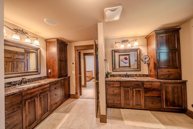 full bath featuring tile patterned flooring, baseboards, two vanities, and a sink