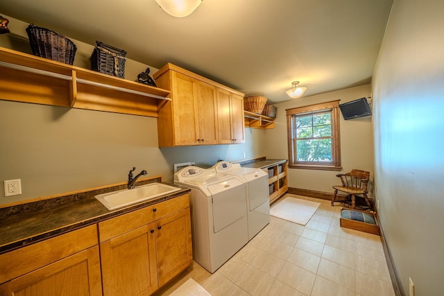 clothes washing area featuring washing machine and clothes dryer, light tile patterned floors, cabinet space, a sink, and baseboards