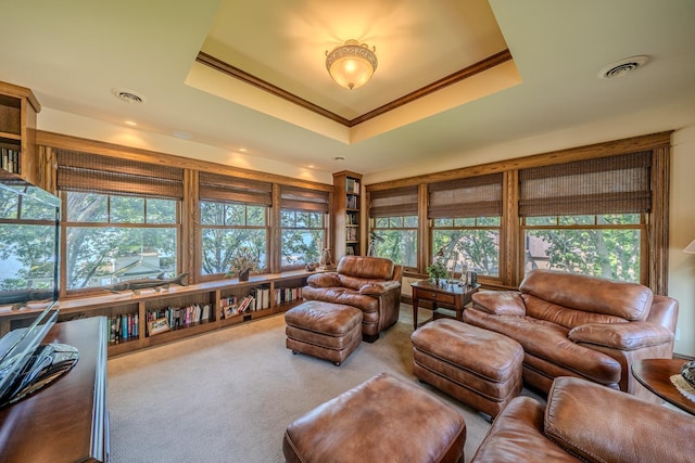 carpeted living room with a raised ceiling, visible vents, and crown molding