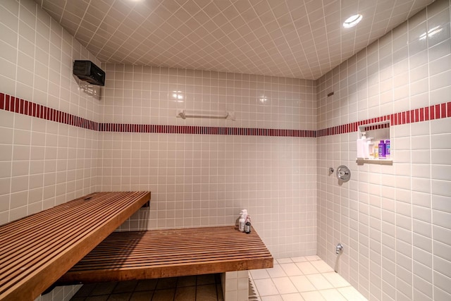 full bath featuring tiled shower, tile walls, and tile patterned floors