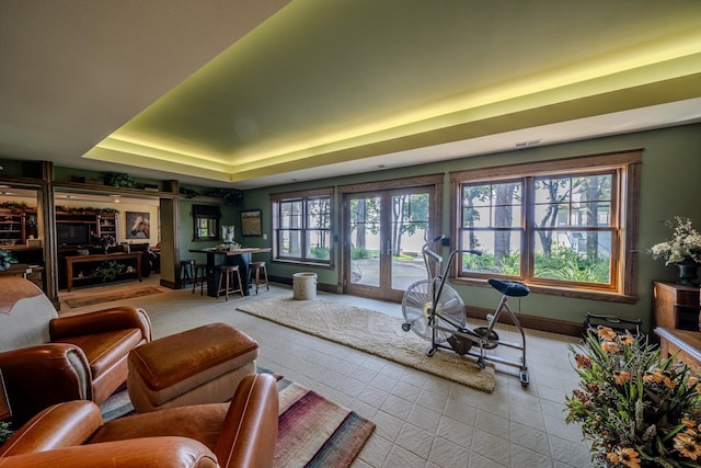 interior space with baseboards, a tray ceiling, and french doors