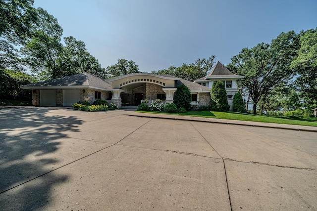 view of front facade with stone siding, driveway, and an attached garage