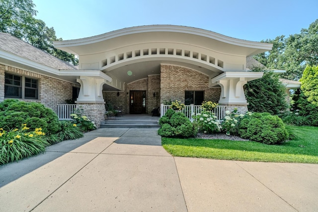 property entrance featuring a porch and brick siding