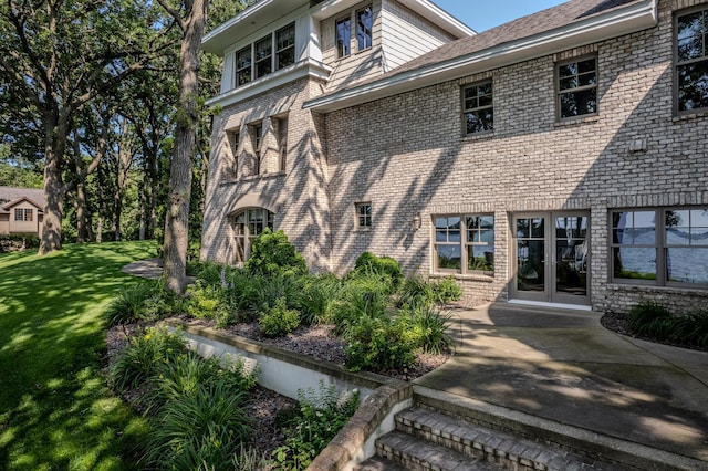 rear view of property with french doors, brick siding, and a yard