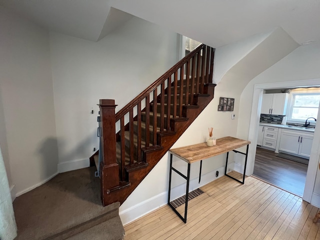 staircase with arched walkways, baseboards, and hardwood / wood-style floors