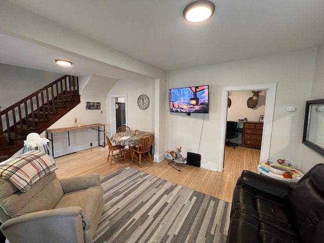 living area featuring stairs, wood finished floors, and baseboards