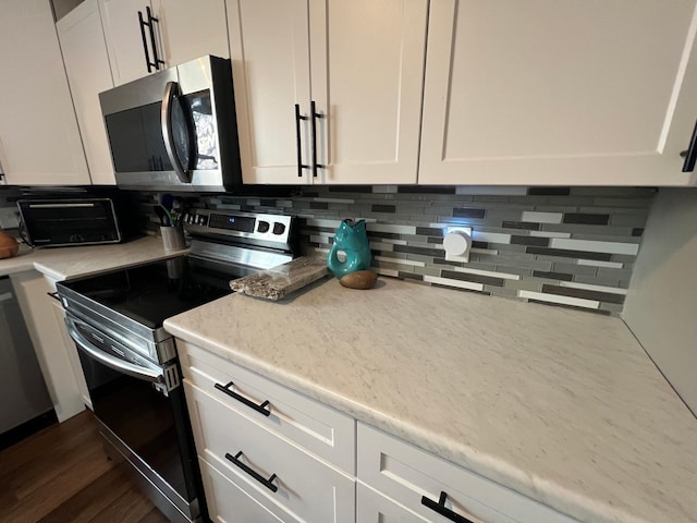 kitchen with decorative backsplash, appliances with stainless steel finishes, white cabinetry, and dark wood-type flooring