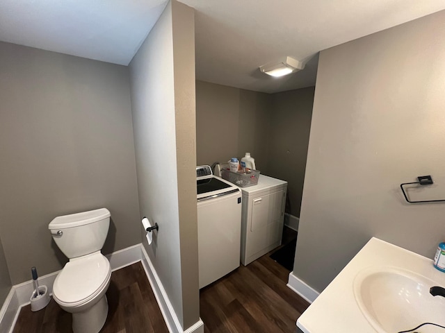 bathroom featuring baseboards, toilet, wood finished floors, independent washer and dryer, and a sink