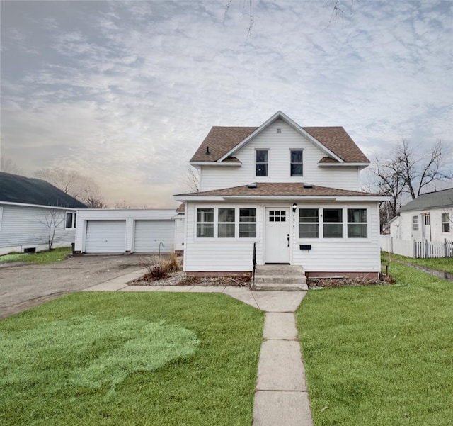 view of front of house featuring a detached garage, a shingled roof, a front lawn, and fence