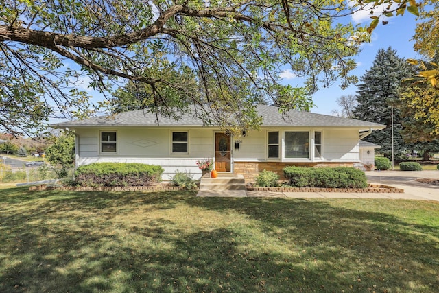 ranch-style home featuring brick siding, a front lawn, and roof with shingles