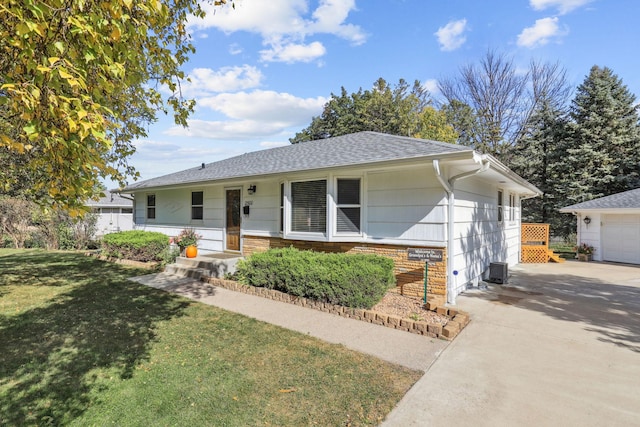 ranch-style home with an outbuilding, stone siding, driveway, roof with shingles, and a front lawn