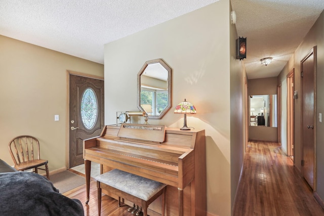 hallway featuring a textured ceiling, baseboards, and wood finished floors