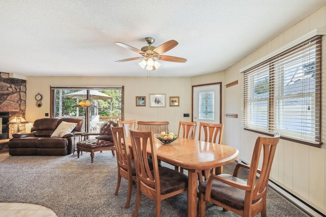 carpeted dining area featuring a textured ceiling, a fireplace, and a ceiling fan