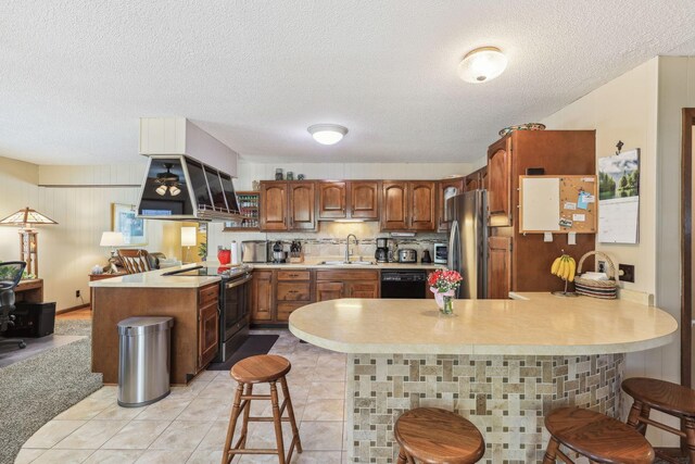 kitchen with a peninsula, a sink, stainless steel appliances, light countertops, and backsplash