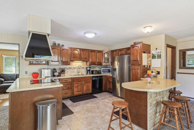 kitchen with light countertops, a sink, a peninsula, black appliances, and extractor fan