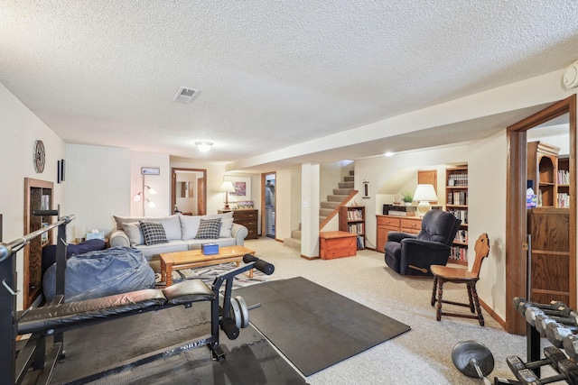 exercise room with light colored carpet, visible vents, and a textured ceiling