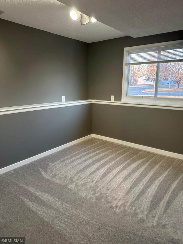 spare room featuring carpet flooring, a textured ceiling, and baseboards