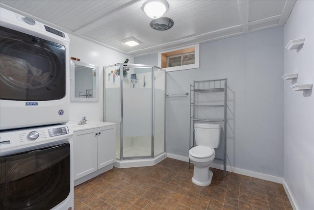 full bath featuring stacked washer and clothes dryer, toilet, a stall shower, vanity, and baseboards