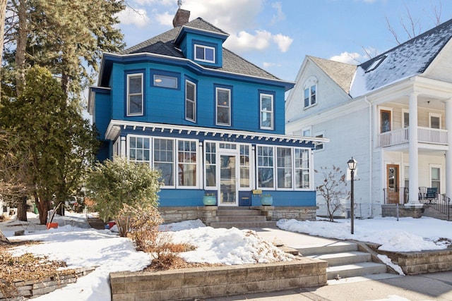 view of front of house featuring a sunroom, a chimney, and entry steps