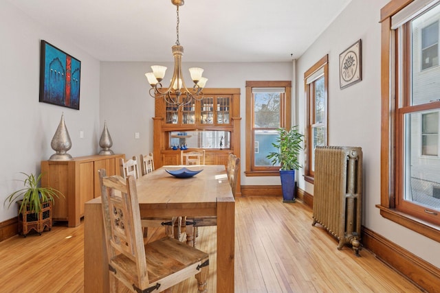 dining space featuring radiator heating unit, light wood-style floors, baseboards, and a chandelier