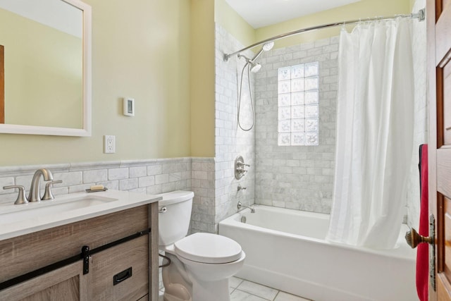 bathroom with vanity, a wainscoted wall, shower / tub combo, tile walls, and toilet