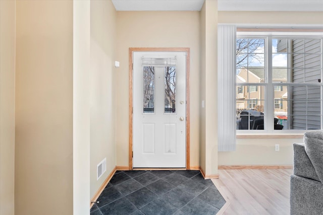 foyer entrance with baseboards, visible vents, and dark wood-type flooring