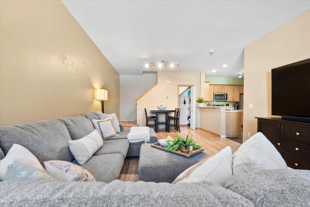 living room with light wood-style floors, a textured ceiling, and recessed lighting