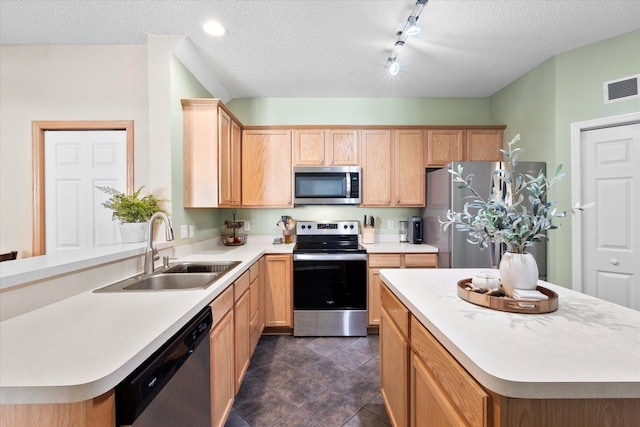 kitchen with a textured ceiling, stainless steel appliances, a sink, visible vents, and light countertops