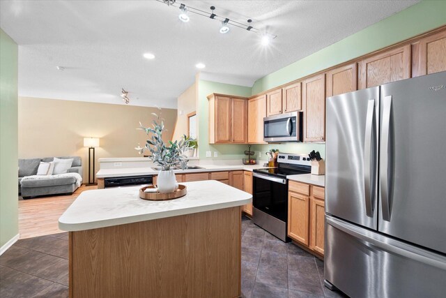 kitchen featuring a center island, light countertops, appliances with stainless steel finishes, open floor plan, and light brown cabinets